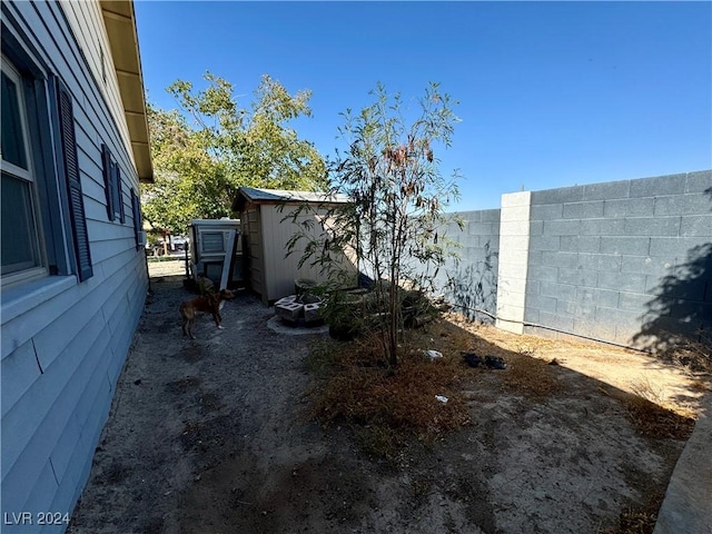 view of yard with an outbuilding, fence, and a shed