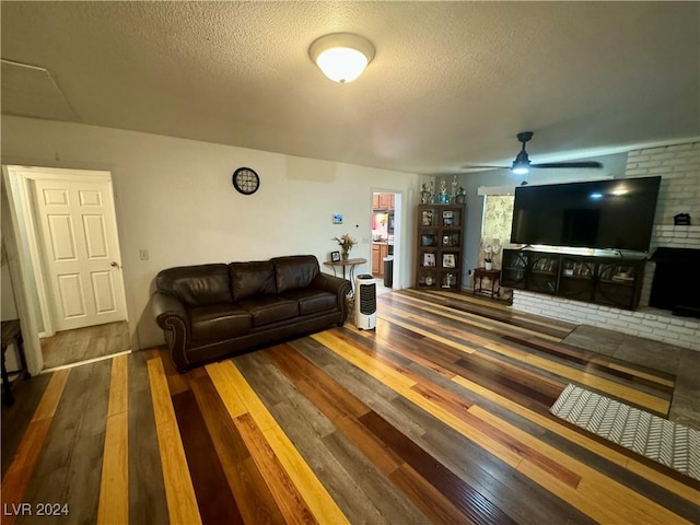 living area featuring wood-type flooring, ceiling fan, and a textured ceiling