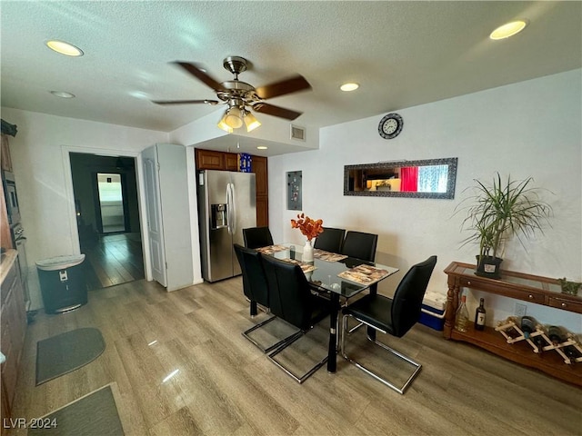 dining area with visible vents, a textured ceiling, and light wood-style flooring