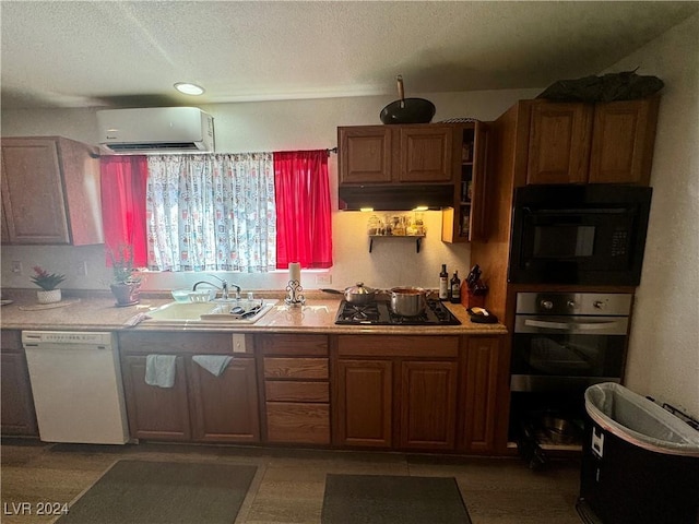 kitchen featuring extractor fan, a sink, light countertops, a wall mounted AC, and black appliances