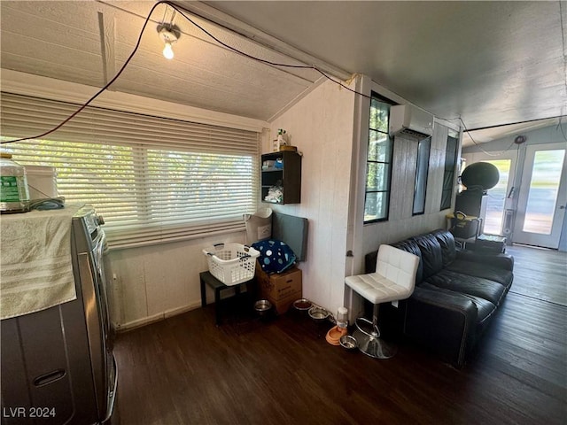 living area with lofted ceiling, a wall mounted AC, and wood finished floors