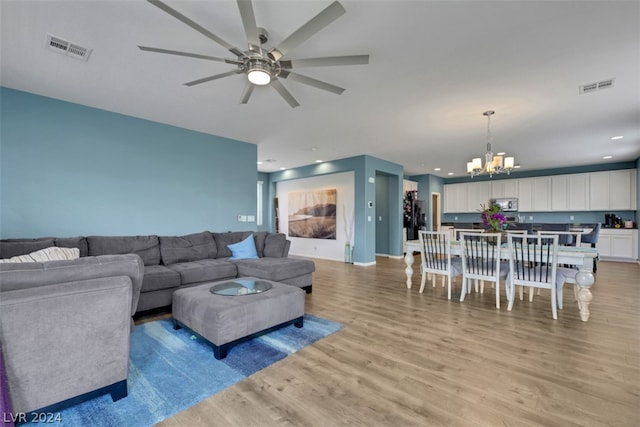 living room with light hardwood / wood-style flooring and ceiling fan with notable chandelier