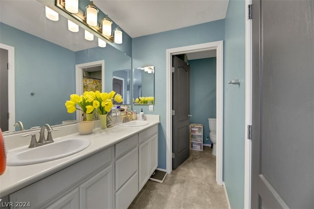 bathroom featuring toilet, double sink vanity, and tile patterned flooring