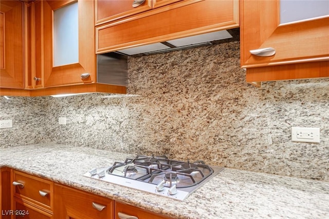 kitchen with decorative backsplash, light stone countertops, white gas stovetop, and ventilation hood