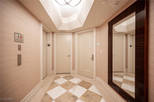 hall with a tray ceiling and elevator