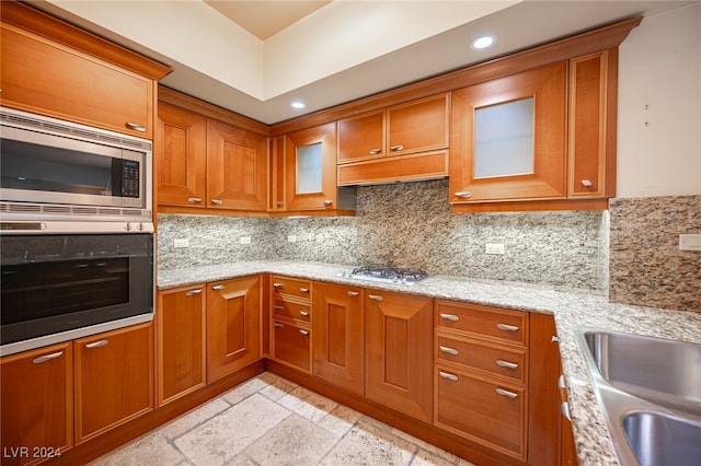 kitchen featuring sink, light stone countertops, stainless steel appliances, and tasteful backsplash