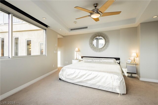 carpeted bedroom featuring ceiling fan and a tray ceiling