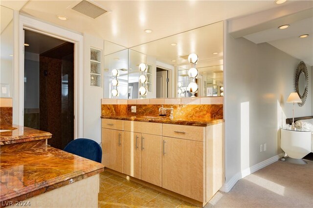 kitchen with dark stone countertops, sink, and light brown cabinets