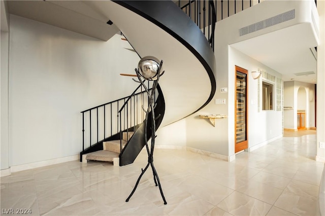 stairway featuring arched walkways, visible vents, a towering ceiling, and baseboards