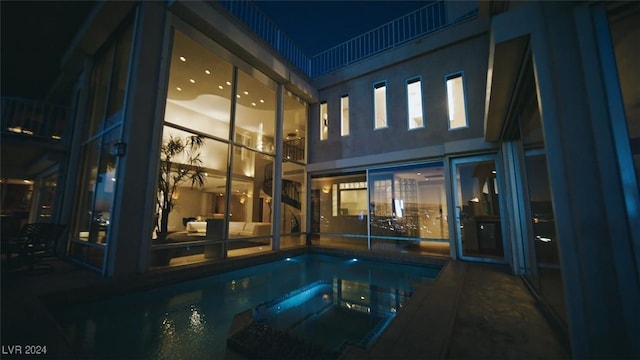 pool at twilight featuring a hot tub