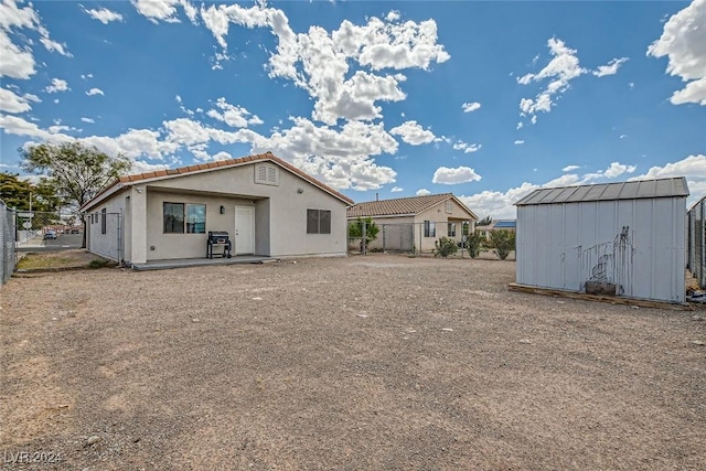 back of house with a storage unit