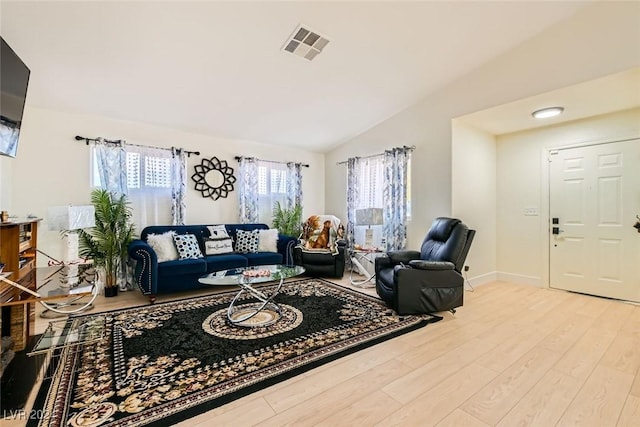 living room with lofted ceiling, plenty of natural light, and light hardwood / wood-style flooring