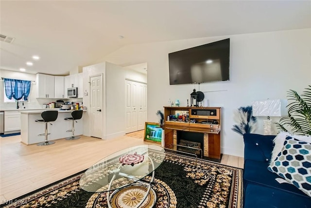 living room with vaulted ceiling and light hardwood / wood-style floors