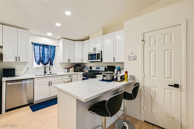 kitchen with sink, white cabinets, a kitchen breakfast bar, kitchen peninsula, and stainless steel appliances