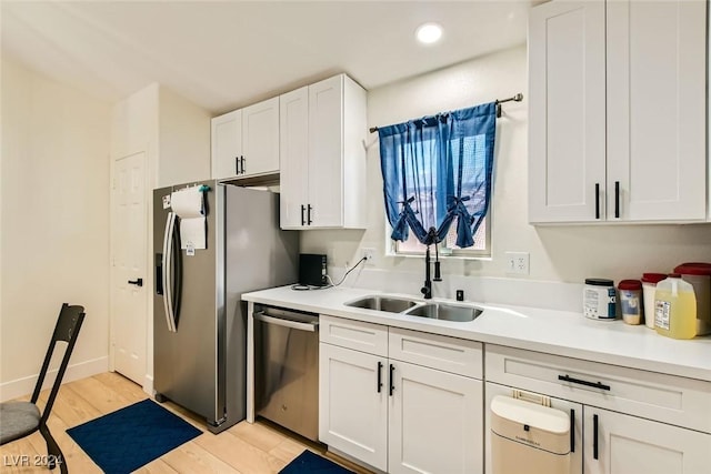 kitchen featuring white cabinetry, sink, light hardwood / wood-style flooring, and appliances with stainless steel finishes