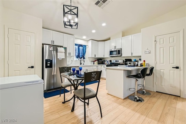 kitchen with a breakfast bar, decorative light fixtures, light hardwood / wood-style flooring, stainless steel appliances, and white cabinets