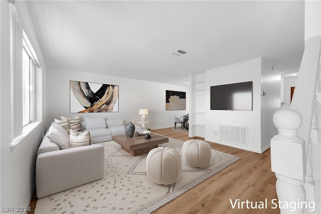 living room with a textured ceiling and light hardwood / wood-style floors