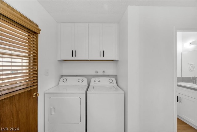 washroom with cabinets, sink, washing machine and dryer, and a textured ceiling