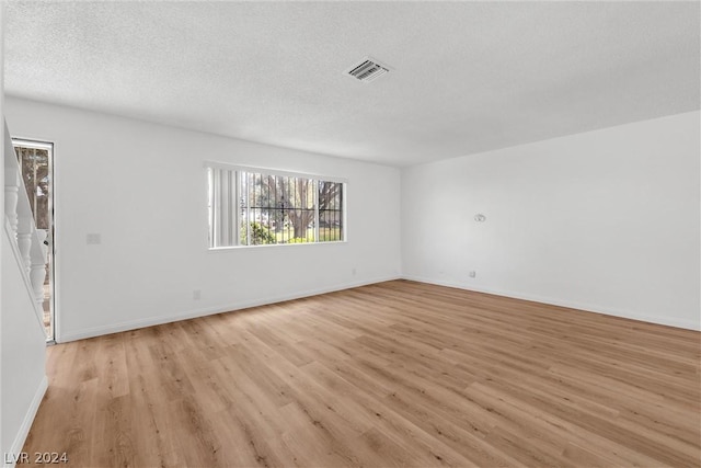 spare room with light hardwood / wood-style flooring and a textured ceiling