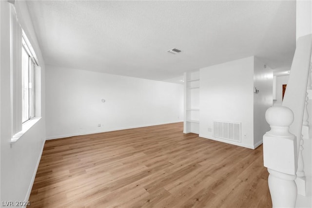 spare room featuring a textured ceiling and light wood-type flooring