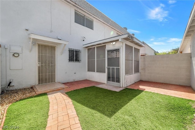 back of property with a lawn and a patio