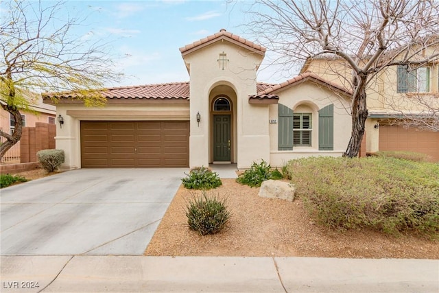 mediterranean / spanish home with a garage, a tile roof, concrete driveway, and stucco siding