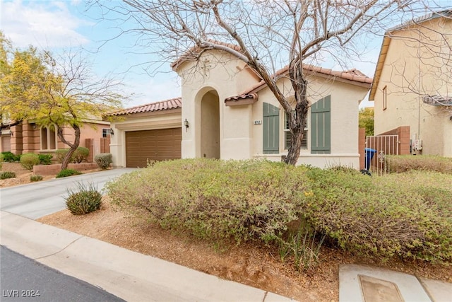 mediterranean / spanish-style home with concrete driveway, an attached garage, a tiled roof, and stucco siding