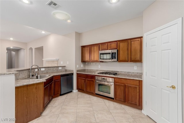 kitchen featuring visible vents, appliances with stainless steel finishes, brown cabinetry, a sink, and a peninsula