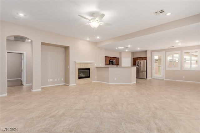 unfurnished living room with a ceiling fan, baseboards, visible vents, and a tiled fireplace