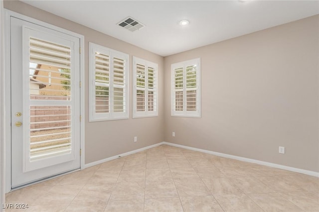 empty room featuring visible vents, baseboards, and light tile patterned floors