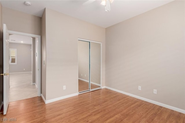 unfurnished bedroom featuring light wood-type flooring, baseboards, and a closet