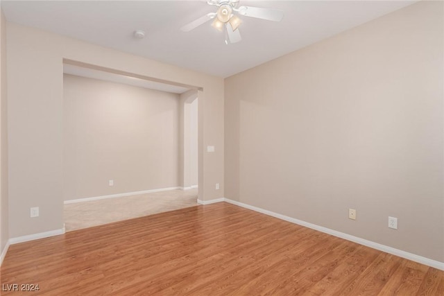 spare room featuring light wood-style floors, baseboards, and a ceiling fan