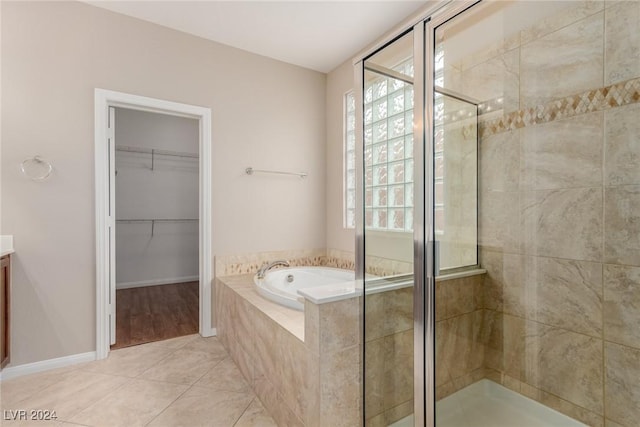 full bath featuring tile patterned flooring, a spacious closet, vanity, a shower stall, and a bath