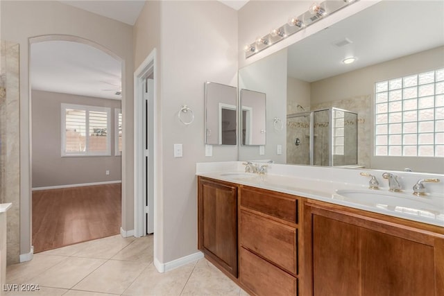 full bath featuring double vanity, a stall shower, a sink, and tile patterned floors