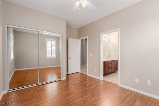 unfurnished bedroom with light wood finished floors, a closet, connected bathroom, and baseboards