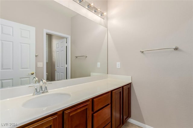 bathroom featuring baseboards, vanity, and toilet