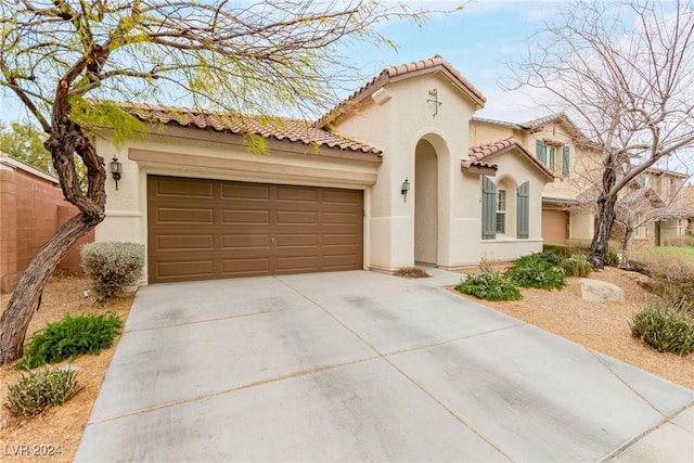 mediterranean / spanish house featuring a garage, driveway, a tile roof, and stucco siding