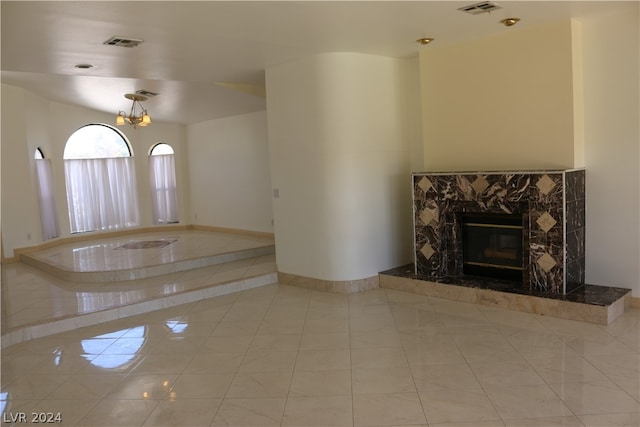 unfurnished living room with light tile patterned flooring, a high end fireplace, and an inviting chandelier