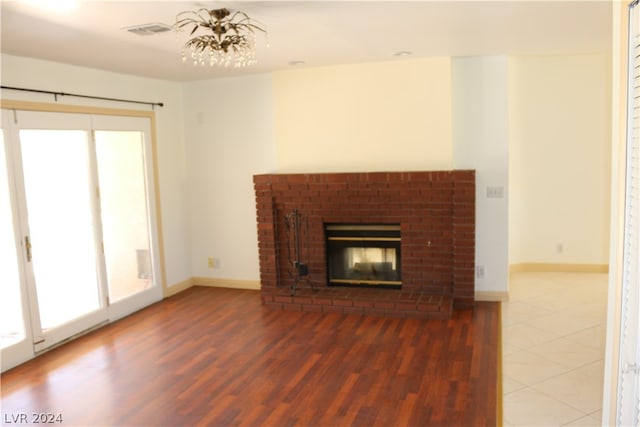 unfurnished living room with a chandelier, hardwood / wood-style flooring, and a fireplace