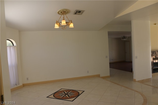 tiled spare room with a notable chandelier