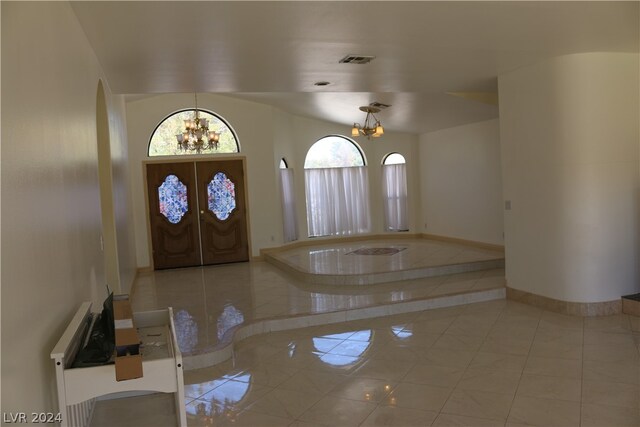 entrance foyer featuring an inviting chandelier, french doors, and light tile patterned floors