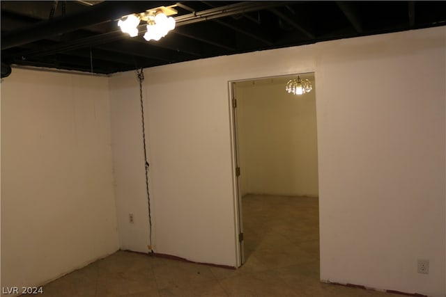 basement featuring light tile patterned floors and a chandelier