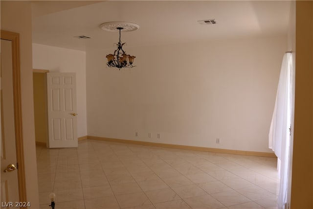 spare room with light tile patterned flooring and a chandelier