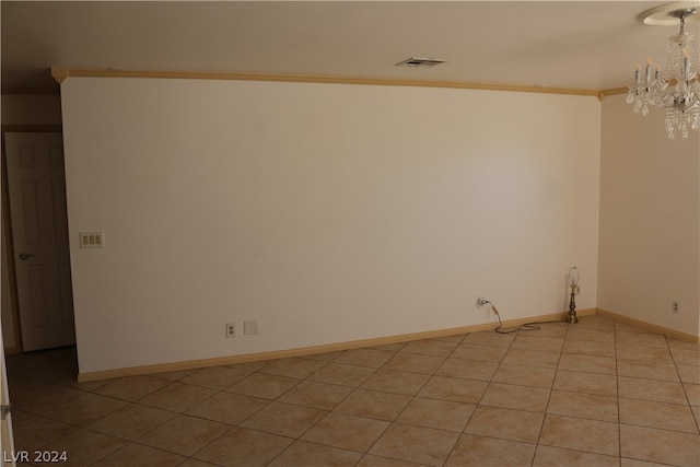 empty room with a notable chandelier, light tile patterned flooring, and ornamental molding