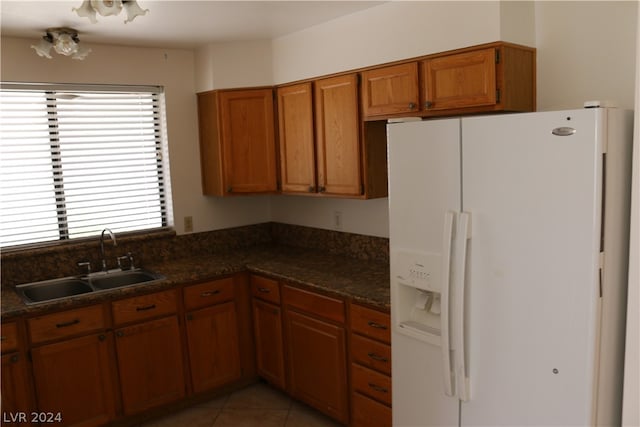 kitchen with light tile patterned flooring, sink, white refrigerator with ice dispenser, and a healthy amount of sunlight