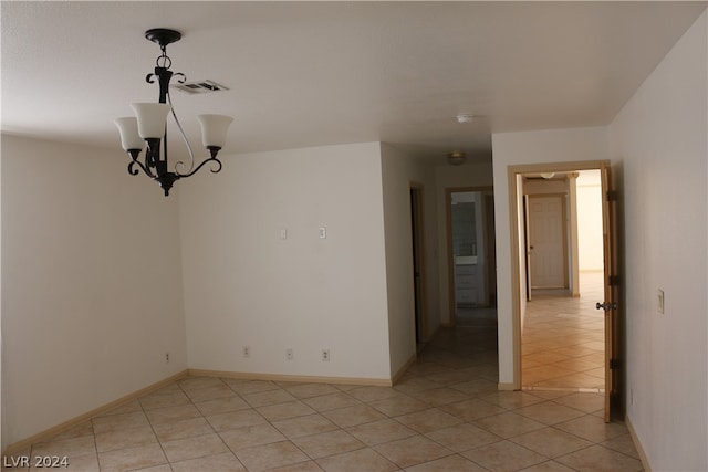 tiled empty room with a notable chandelier