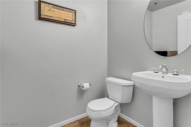 half bathroom featuring a sink, toilet, and baseboards