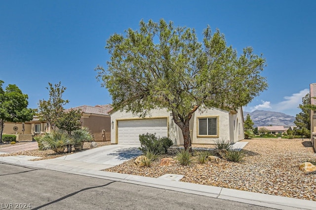 view of property hidden behind natural elements featuring a garage and a mountain view