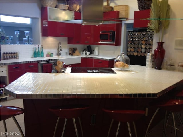 kitchen featuring decorative backsplash, island range hood, stainless steel dishwasher, and a kitchen bar