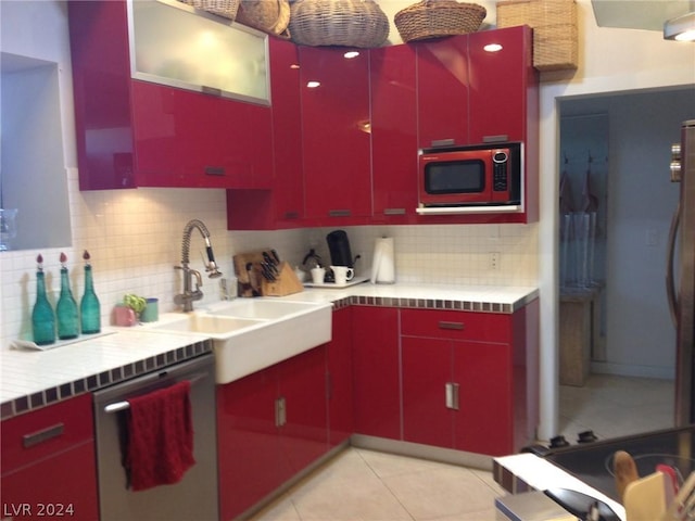 kitchen with stainless steel appliances, sink, light tile patterned floors, and decorative backsplash